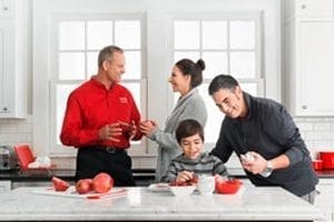 family in kitchen talking to HVAC worker